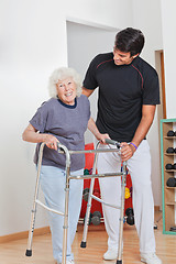 Image showing Senior Woman Holding Walker While Trainer Assisting Her