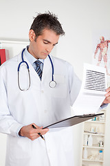 Image showing Male Doctor Looking at Clipboard