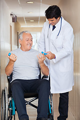 Image showing Doctor Giving Hand Weights To The Senior Man Sitting In a Wheelc