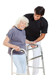 Image showing Senior Woman Holding Walker While Trainer Assisting Her