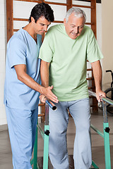 Image showing Therapist Assisting Senior Man To Walk With The Support Of Bars