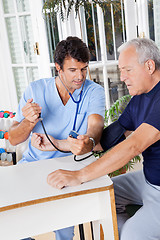 Image showing Male Nurse Checking Blood Pressure Of a Senior Patient