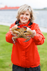 Image showing Happy woman showing alive crab outdoors