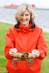 Image showing Happy woman showing alive crab outdoors