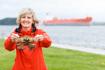 Image showing Happy woman showing alive crab outdoors