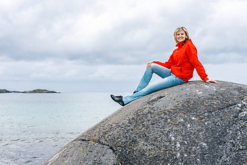 Image showing Woman sitting on stone against sea background