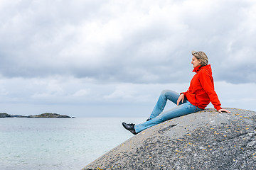 Image showing Woman sitting on stone and enjoying sea view