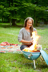 Image showing Female Preparing Meal On Flaming Barbecue
