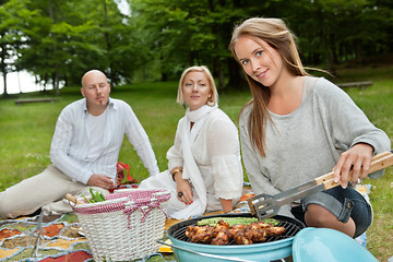 Image showing Female Cooking Meat On Portable Barbecue