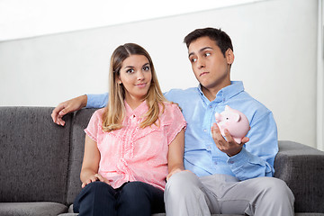 Image showing Man Holding Piggybank While Sitting With Woman