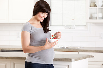 Image showing Pregnant Woman in Kitchen Eating Snack