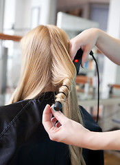 Image showing Stylist Curling Womans Hair