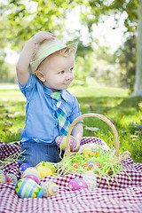 Image showing Cute Little Boy Outside Holding Easter Eggs Tips His Hat