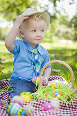 Image showing Cute Little Boy Outside Holding Easter Eggs Tips His Hat