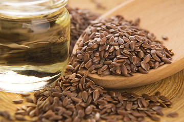 Image showing Linseed oil and flax seeds on wooden background 