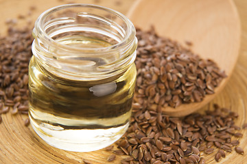 Image showing Linseed oil and flax seeds on wooden background 