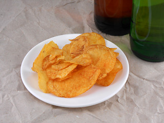 Image showing Beer bottle and potato chips on white plate