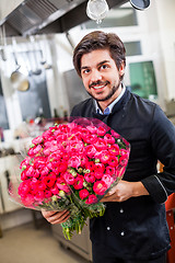 Image showing Smiling chef holding bunches of fresh flowers