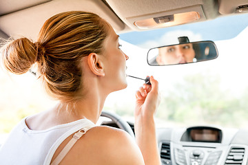 Image showing Beautiful woman applying makeup in the car