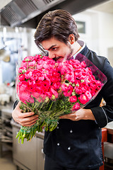 Image showing Smiling chef holding bunches of fresh flowers