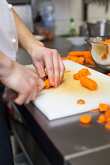 Image showing Chef in uniform preparing fresh carrot batons