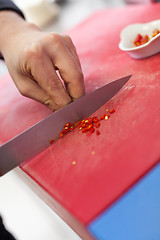 Image showing Chef dicing red hot chili peppers