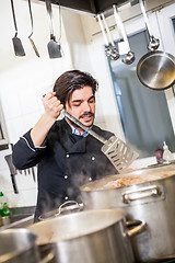 Image showing Chef stirring a huge pot of stew or casserole