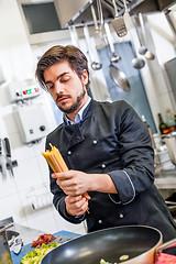 Image showing Attractive friendly chef preparing spaghetti