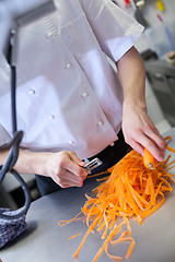 Image showing Chef in uniform preparing fresh carrot batons