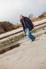 Image showing Elderly energetic man running along a beach