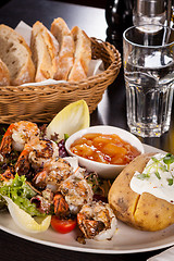 Image showing Grilled prawns with endive salad and jacket potato