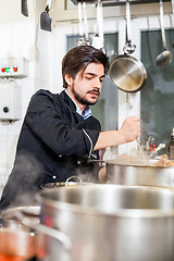 Image showing Chef stirring a huge pot of stew or casserole