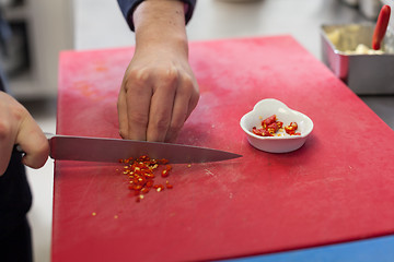 Image showing Chef dicing red hot chili peppers