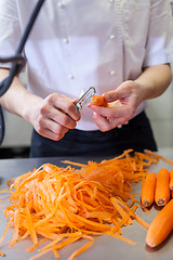 Image showing Chef in uniform preparing fresh carrot batons