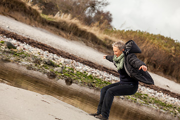 Image showing Happy senior woman frolicking on the beach