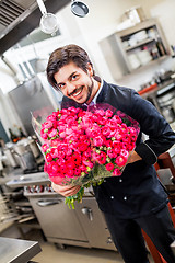 Image showing Smiling chef holding bunches of fresh flowers