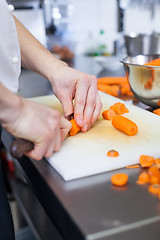 Image showing Chef in uniform preparing fresh carrot batons