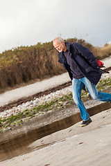 Image showing Elderly energetic man running along a beach