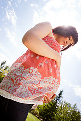 Image showing Pregnant Woman in Park Looking at Belly