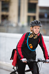 Image showing Young Woman Riding Bicycle With Courier Delivery Bag