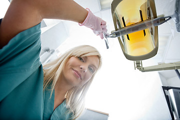 Image showing Female Dentist Adjusting Electric Light At Clinic