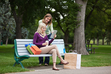 Image showing Women With Shopping Bags Using Tablet PC At Park