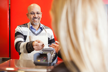 Image showing Mature Man Accepting Credit Card From Young Woman At Supermarket