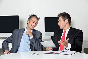 Image showing Businessman Holding Digital Tablet Sitting With Colleague At Des