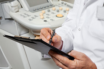 Image showing Male Doctor Writing On Clipboard