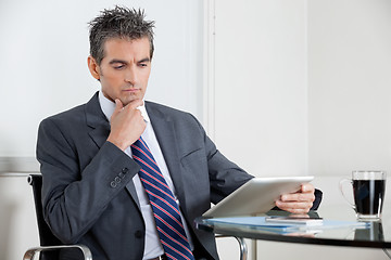 Image showing Contemplative Businessman Using Digital Tablet In Office