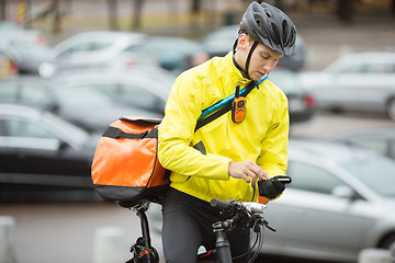 Image showing Male Cyclist With Courier Bag Using Mobile Phone On Street