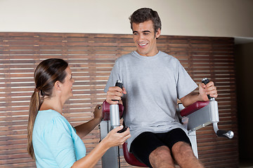 Image showing Man Using An Exercise Machine While Looking At Instructor