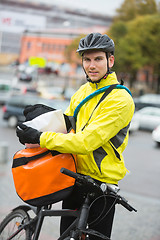 Image showing Male Cyclist Putting Package In Courier Bag On Street