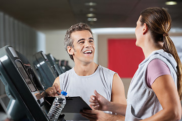 Image showing Happy Instructor Looking At Female Client Exercising On Treadmil